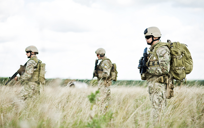 soldiers with combat gear walking in field